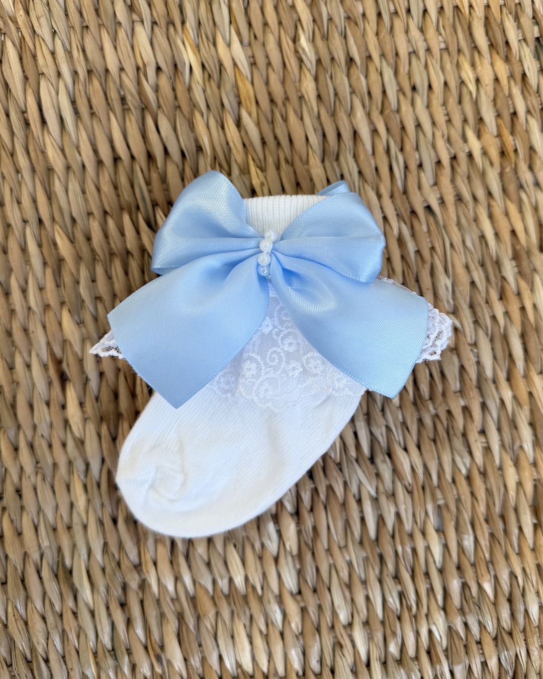 Crafted in soft white fabric, each pair features a delicate lace frill trim, finished with a pretty satin side bow and elegant pearl chain centre.