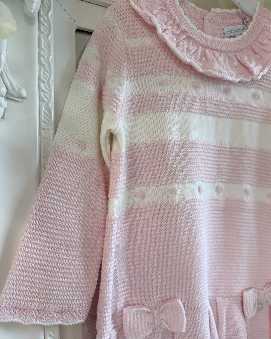 Bluesbaby Marie baby pink and cream knitted girls dress with frill collar, bows and pleated skirt.