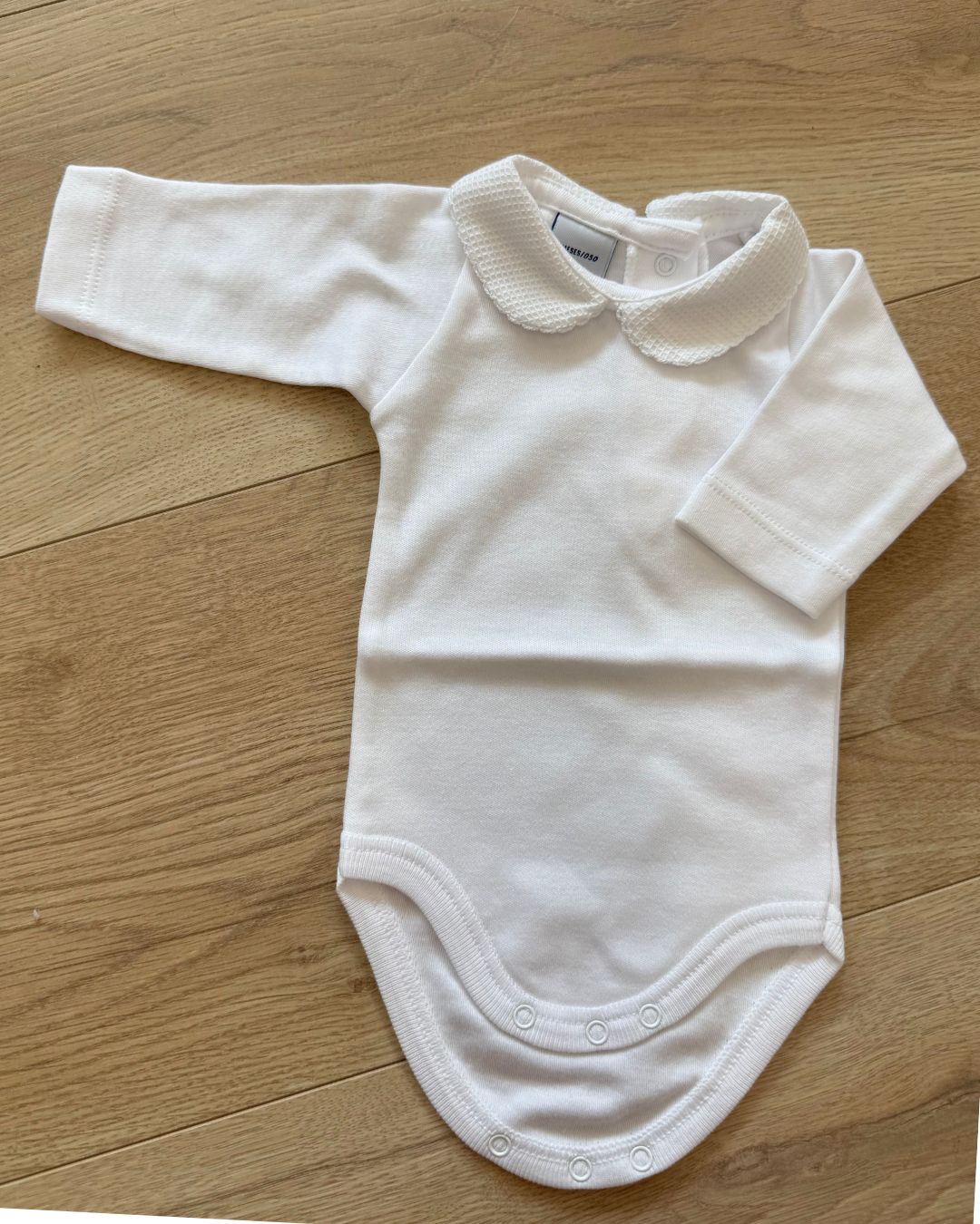 Babidu white long sleeve baby vest with textured Peter Pan collar.