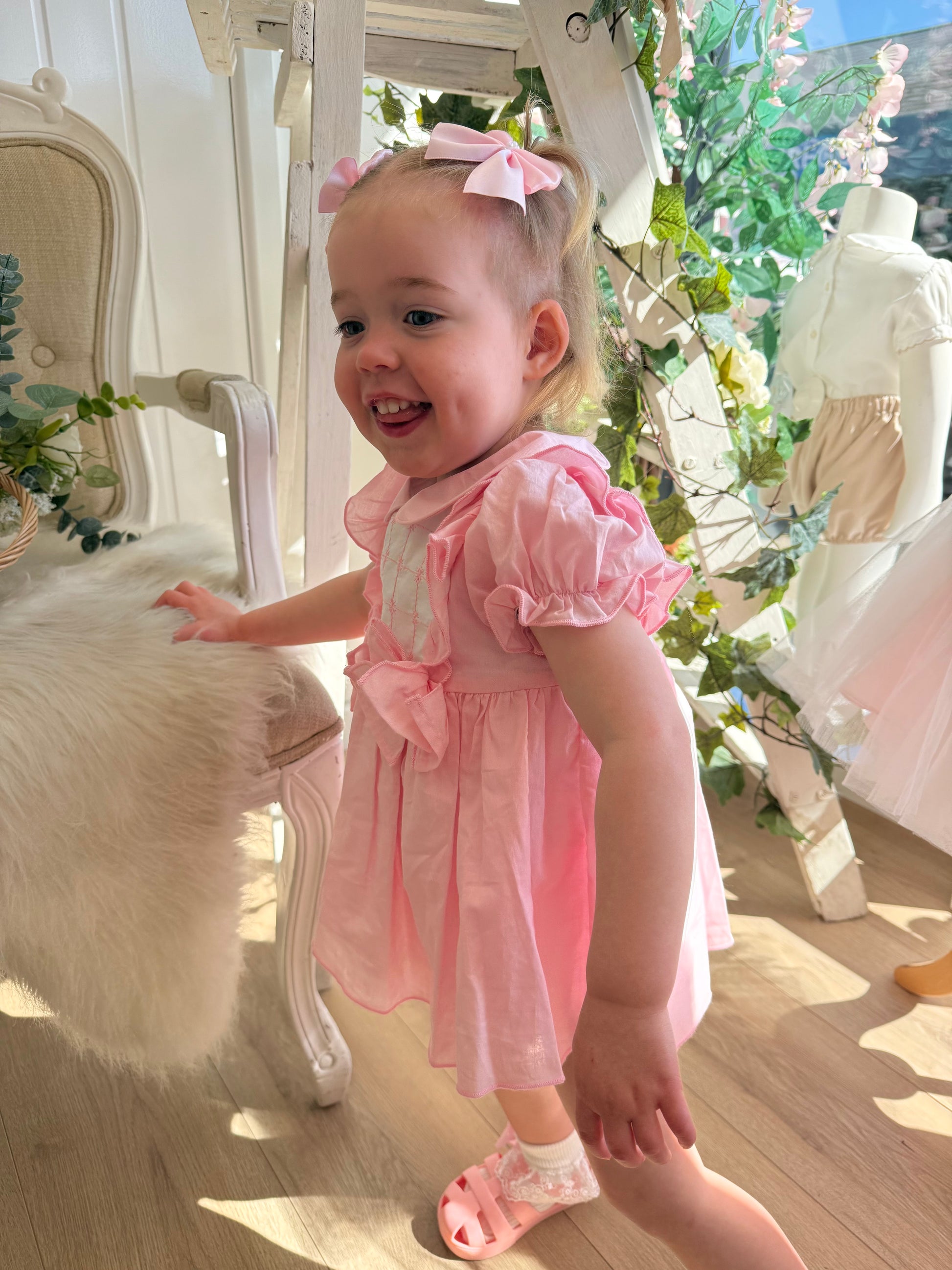 A soft rosy pink, this traditional Spanish-style dress is paired with matching jam pants. Adorned with a white chest panel featuring subtle stitch detailing, the dress is finished with pretty shoulder frills, two bow accents and a classic Peter Pan collar.