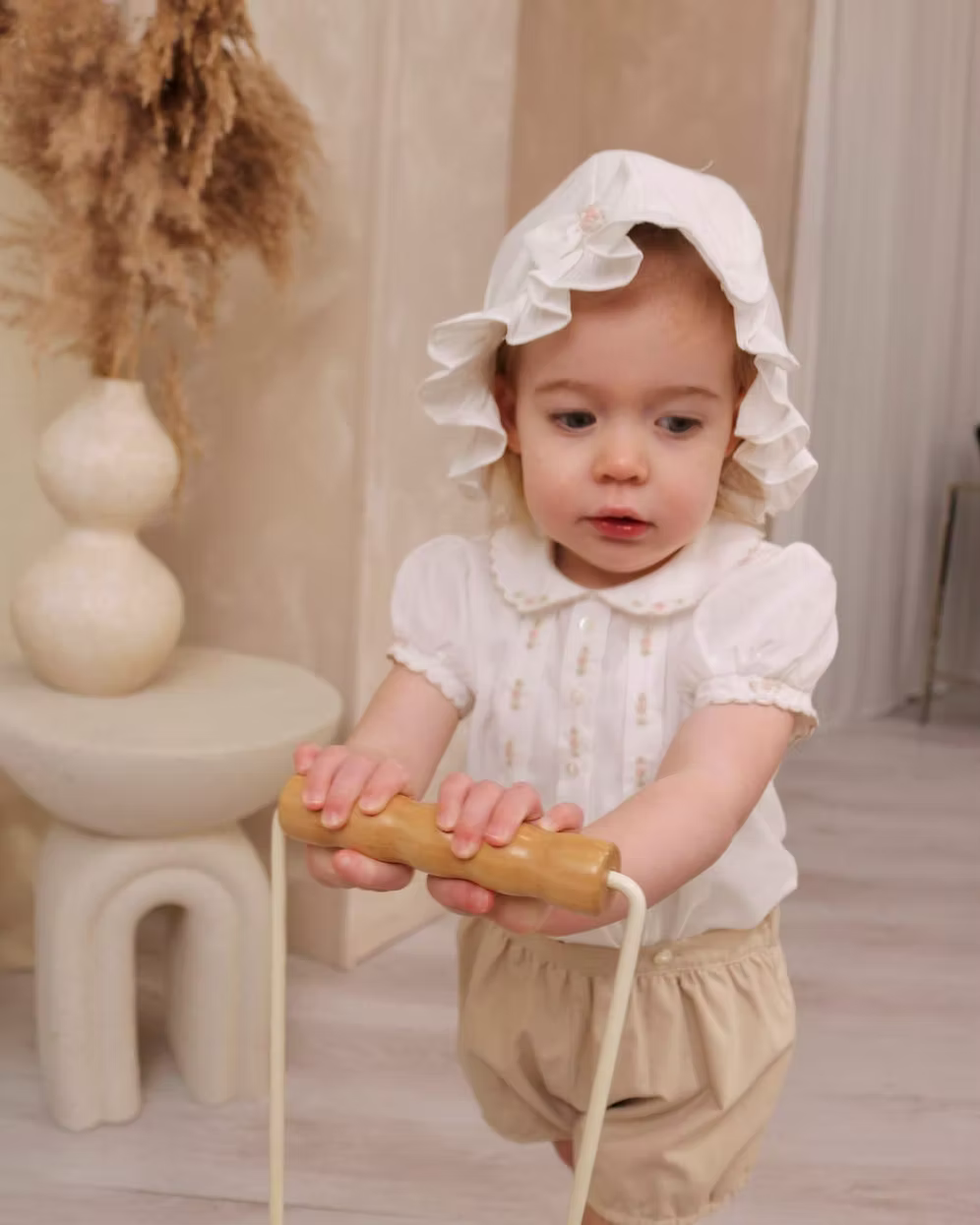 Sarah Louise x Little Lambs Heritage Ruffle Hat featuring soft ivory fabric, delicate ruffle trim and subtle embroidered detailing.