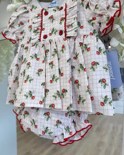 Off-white and pink check baby dress with strawberry print, frill chest detail, puff sleeves, red stitch trims, matching pants, and bow back fastening.