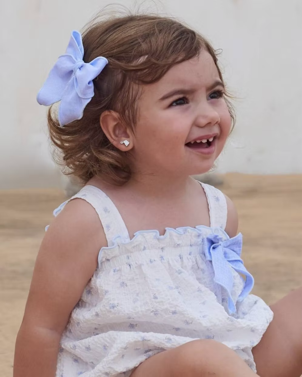 Blue Flower Romper. Designed in a soft white crinkle-textured fabric, this delicate piece is adorned with dainty blue floral detailing