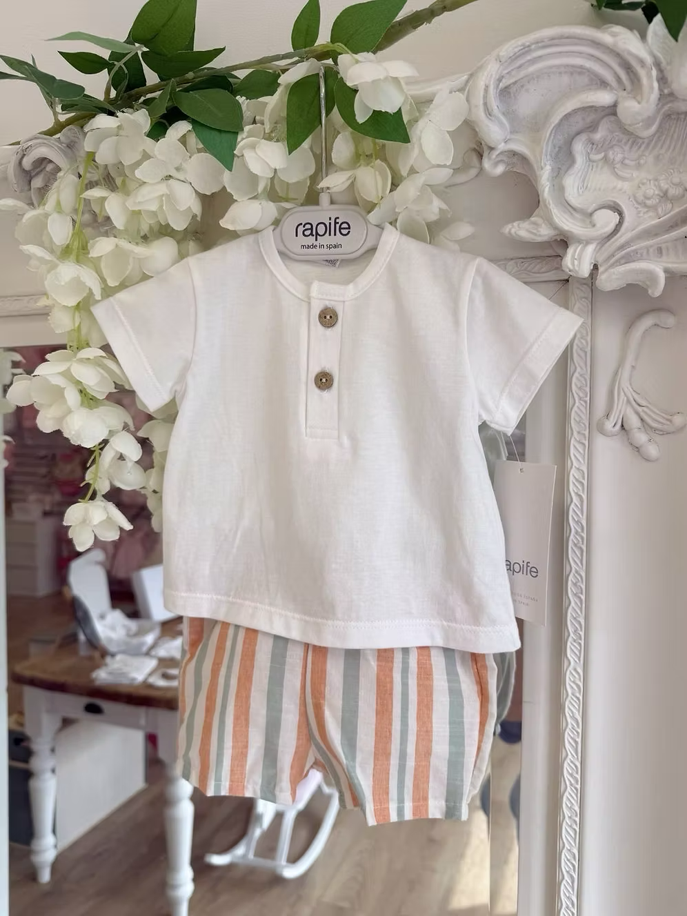 featuring striped shorts in soft off-white with pops of green and orange. Paired perfectly with a crisp white tee, finished with a simple wooden button neckline