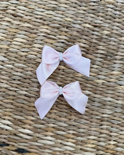 Featuring a small structured bow with a pearl-beaded centre, each clip is secured on a crocodile-style clasp for easy styling and a secure hold. 