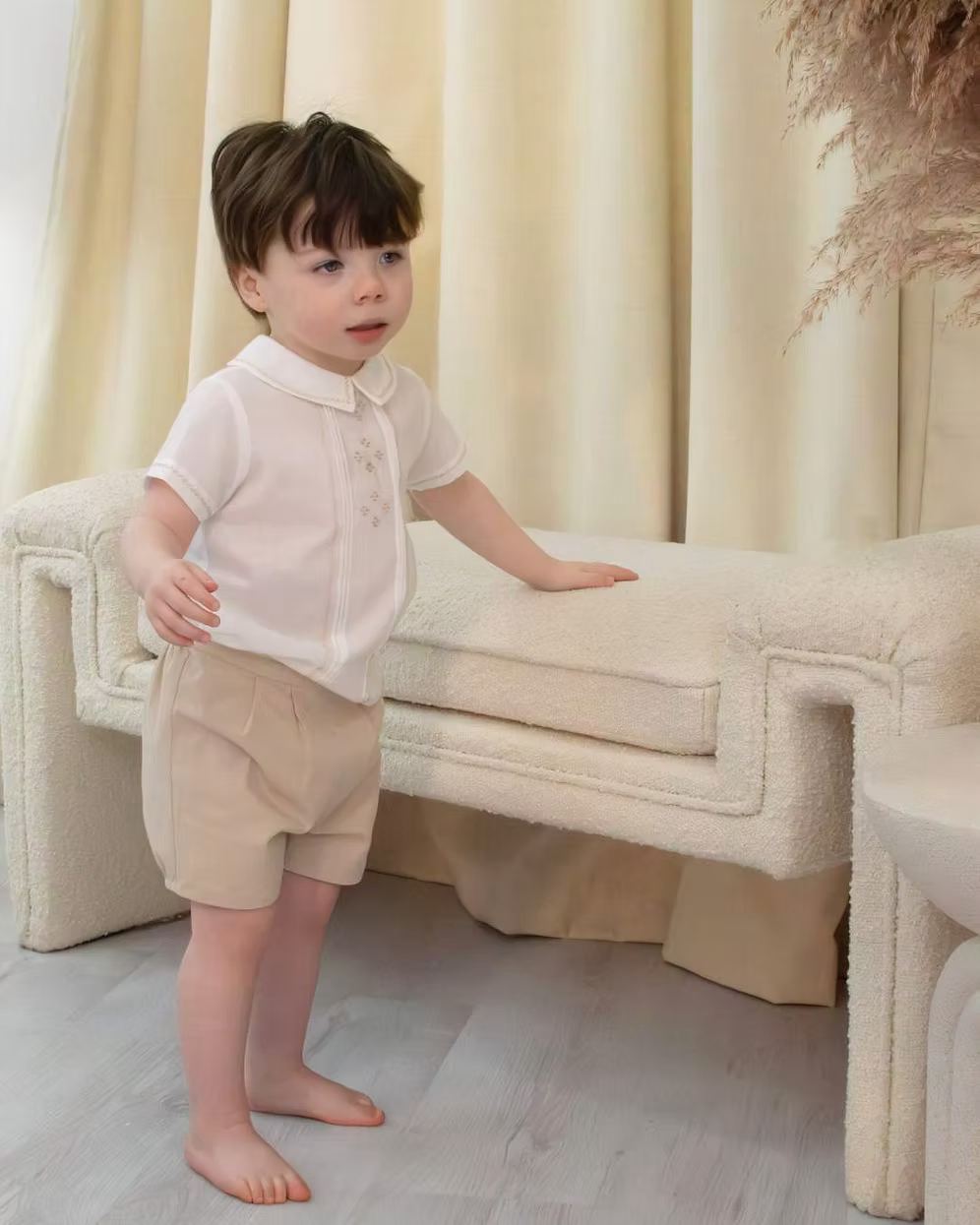 Sarah Louise x Little Lambs Heritage Boys Short Set featuring an ivory shirt with traditional detailing and tailored beige shorts.