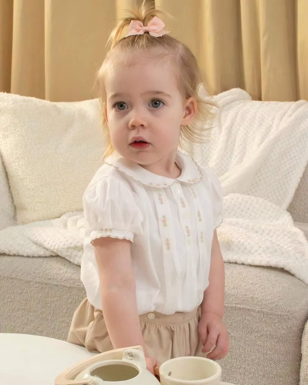 Sarah Louise x Little Lambs Heritage Girls Short Set featuring an ivory hand-smocked blouse with peach embroidery and neutral tailored shorts.