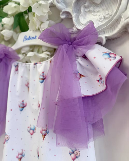 Babine Lilac Dream Dress featuring an ice cream, balloon and cupcake print, lilac tulle bows, frill sleeves, pom pom hem trim and scoop back tie.