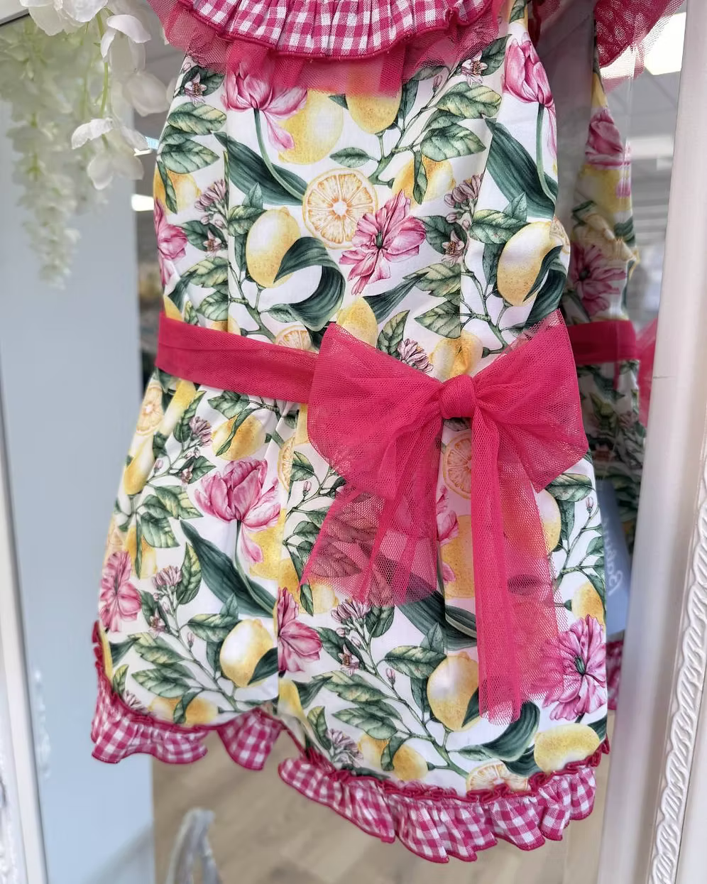 Babine Lemon Blossom Playsuit featuring a lemon and pink floral print, open back, tulle frill spine detail, gingham collar and statement bow tie.