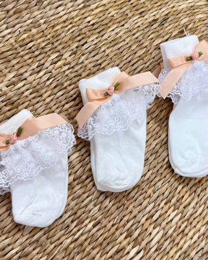 Little Lambs Frill Ankle Socks featuring white fabric, lace frill detailing, peach satin side bow and elegant rose centre.