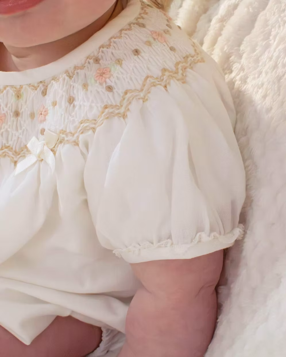 Sarah Louise x Little Lambs Heritage Bubble Romper featuring ivory fabric, hand-smocked floral embroidery, puff sleeves and a classic bubble shape.
