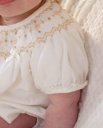 Sarah Louise x Little Lambs Heritage Bubble Romper featuring ivory fabric, hand-smocked floral embroidery, puff sleeves and a classic bubble shape.