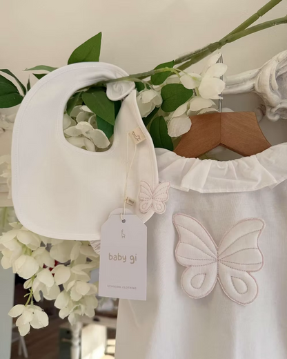 Baby Gi Butterfly Back Romper featuring a white bubble design, oversized butterfly back detail, pink embroidered trims and a frill collar. Alongside with the matching bib.