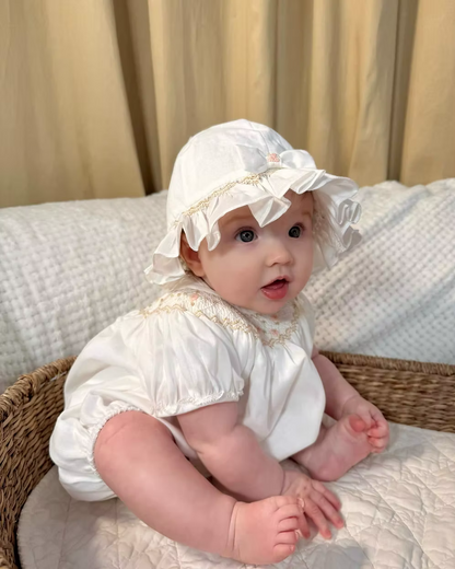 Sarah Louise x Little Lambs Heritage Bubble Romper featuring ivory fabric, hand-smocked floral embroidery, puff sleeves and a classic bubble shape.