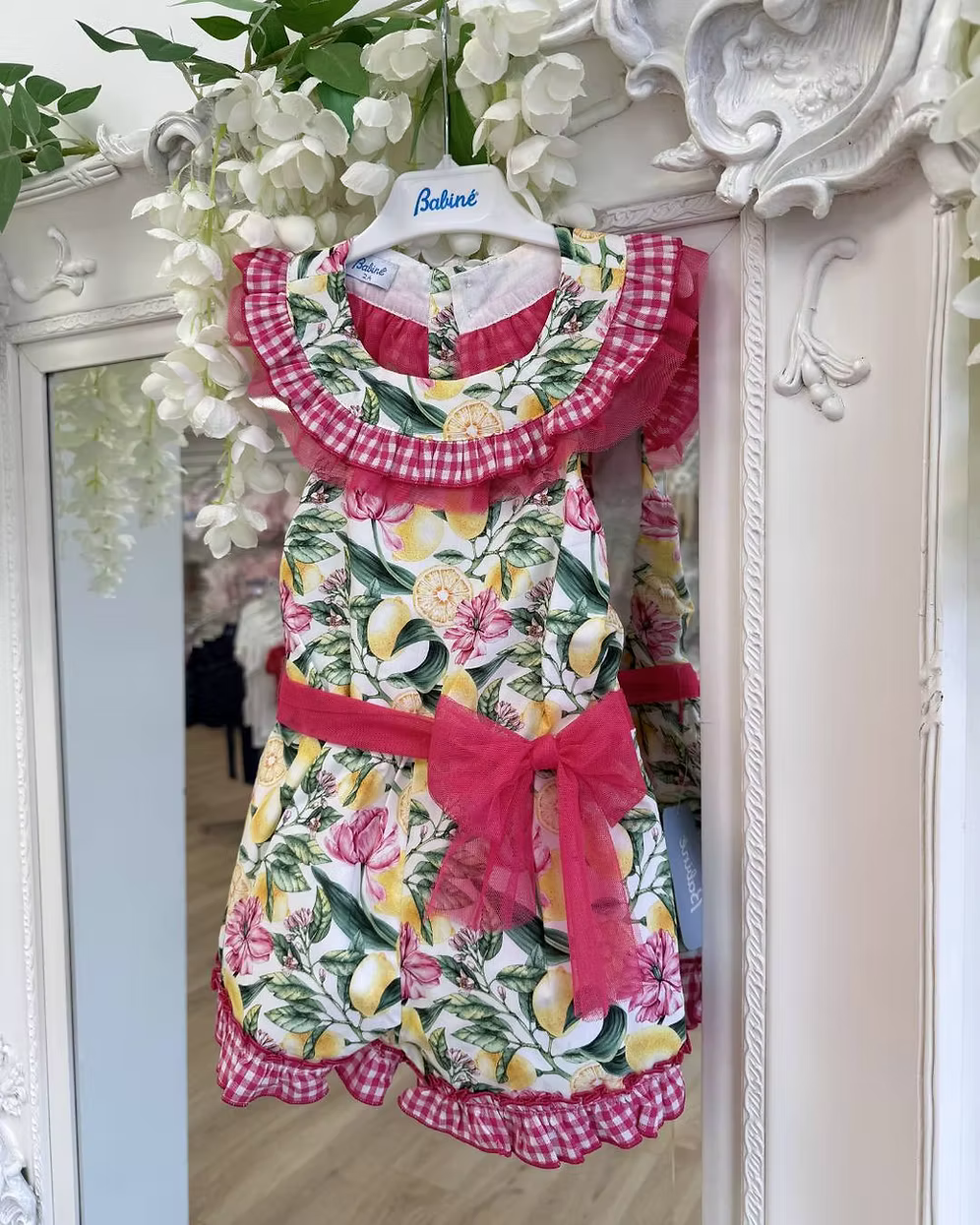 Babine Lemon Blossom Playsuit featuring a lemon and pink floral print, open back, tulle frill spine detail, gingham collar and statement bow tie.