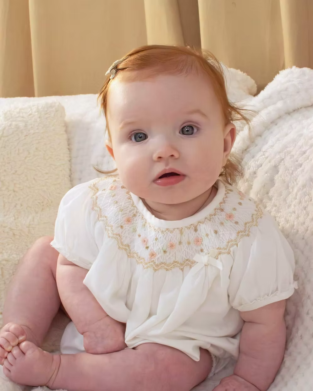 Sarah Louise x Little Lambs Heritage Bubble Romper featuring ivory fabric, hand-smocked floral embroidery, puff sleeves and a classic bubble shape.