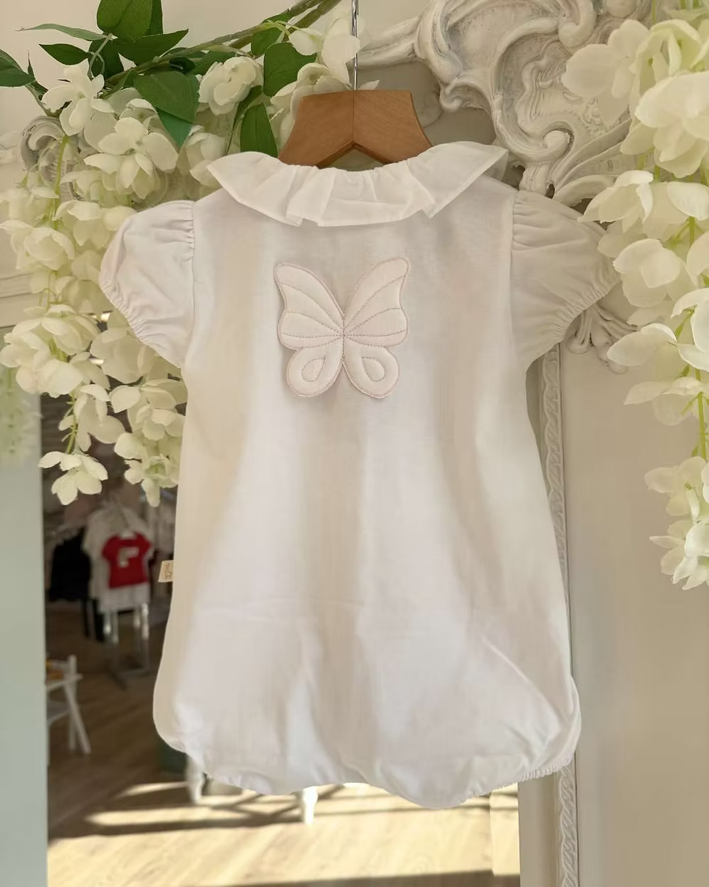 Baby Gi Butterfly Back Romper featuring a white bubble design, oversized butterfly back detail, pink embroidered trims and a frill collar.