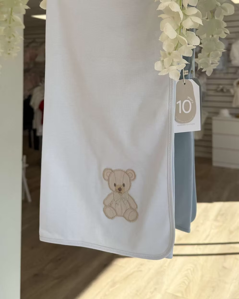 Baby Gi Teddy Shawl featuring soft cotton fabric, embroidered teddy bear detail and available in ivory, pink and blue colourways.