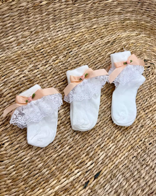 Little Lambs Frill Ankle Socks featuring white fabric, lace frill detailing, peach satin side bow and elegant rose centre.