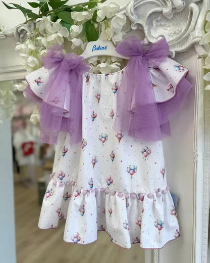 Babine Lilac Dream Dress featuring an ice cream, balloon and cupcake print, lilac tulle bows, frill sleeves, pom pom hem trim and scoop back tie.