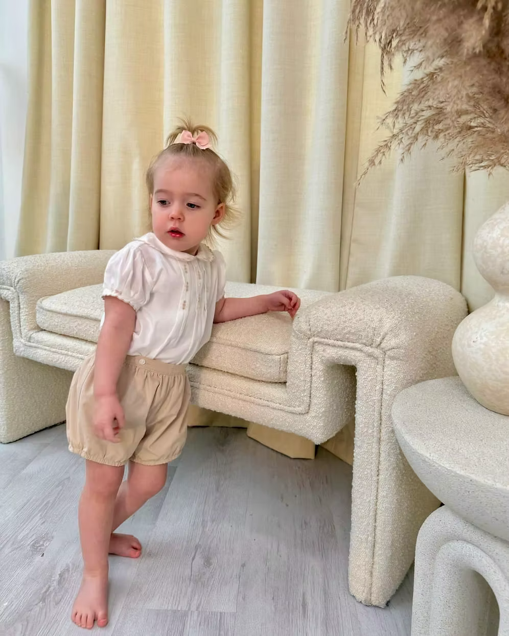 Sarah Louise x Little Lambs Heritage Girls Short Set featuring an ivory hand-smocked blouse with peach embroidery and neutral tailored shorts.