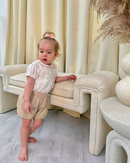 Sarah Louise x Little Lambs Heritage Girls Short Set featuring an ivory hand-smocked blouse with peach embroidery and neutral tailored shorts.
