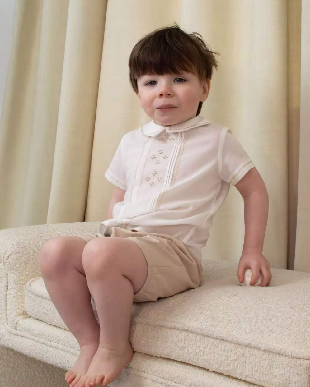Sarah Louise x Little Lambs Heritage Boys Short Set featuring an ivory shirt with traditional detailing and tailored beige shorts.