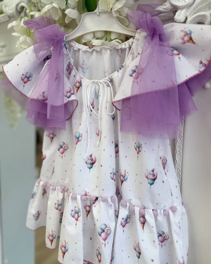 Babine Lilac Dream Dress featuring an ice cream, balloon and cupcake print, lilac tulle bows, frill sleeves, pom pom hem trim and scoop back tie.
