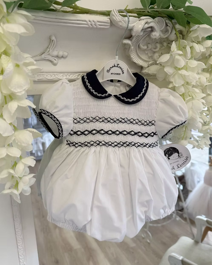 Baby girls white bubble romper with navy Peter Pan collar, sleeve trim and full smocked chest