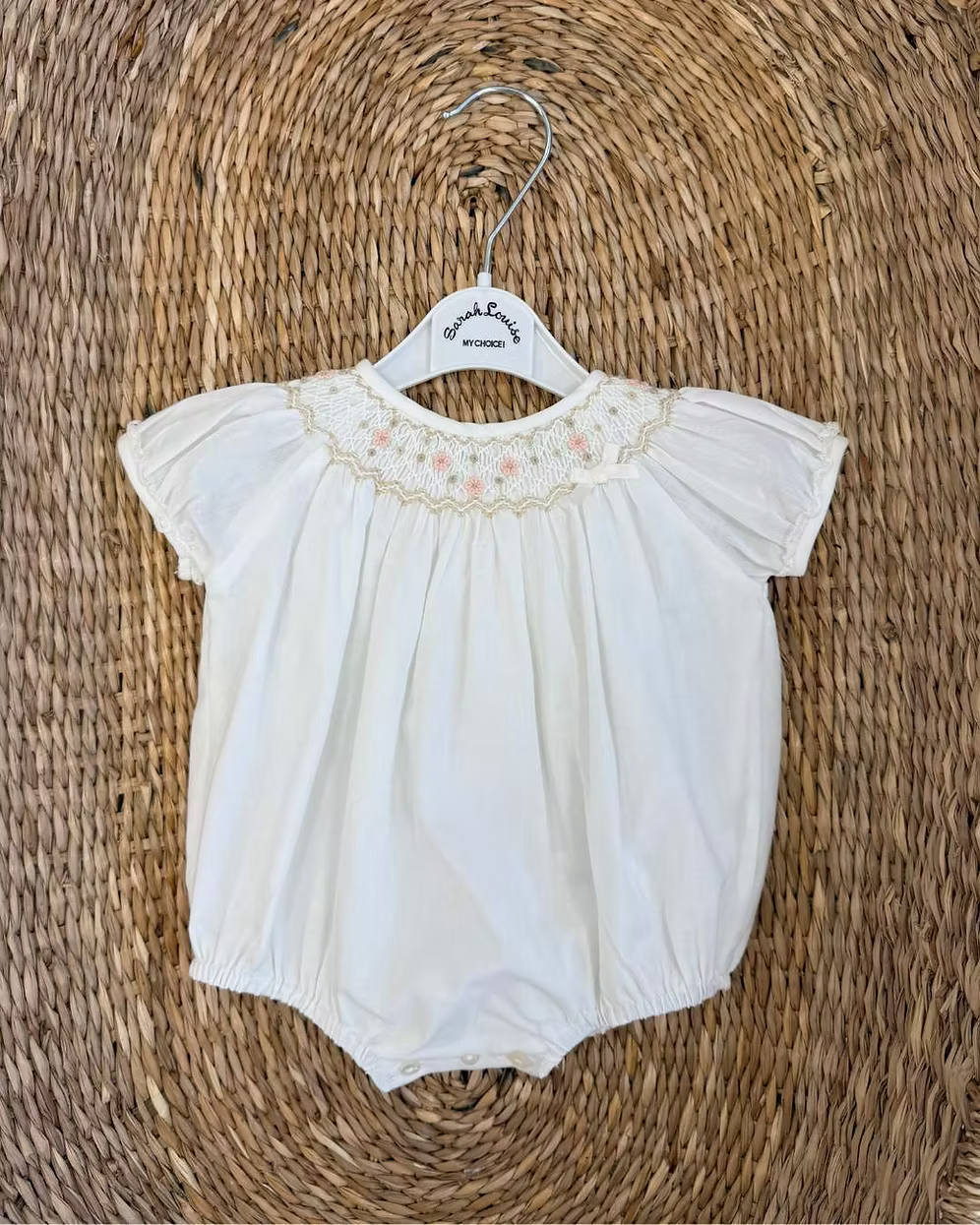 Sarah Louise x Little Lambs Heritage Bubble Romper featuring ivory fabric, hand-smocked floral embroidery, puff sleeves and a classic bubble shape.