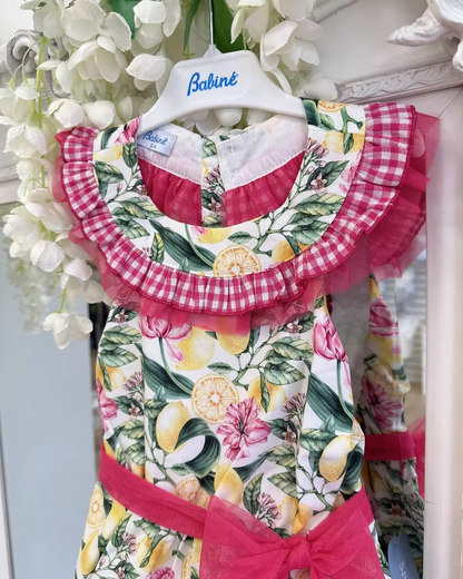 Babine Lemon Blossom Playsuit featuring a lemon and pink floral print, open back, tulle frill spine detail, gingham collar and statement bow tie.
