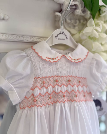 White smocked dress with peach smocking, embroidered florals and scalloped hems