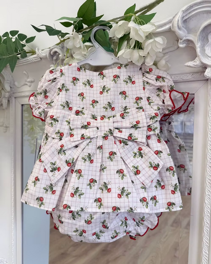 Off-white and pink check baby dress with strawberry print, frill chest detail, puff sleeves, red stitch trims, matching pants, and bow back fastening.