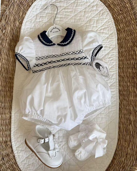 Baby girls white bubble romper with navy Peter Pan collar, sleeve trim and full smocked chest