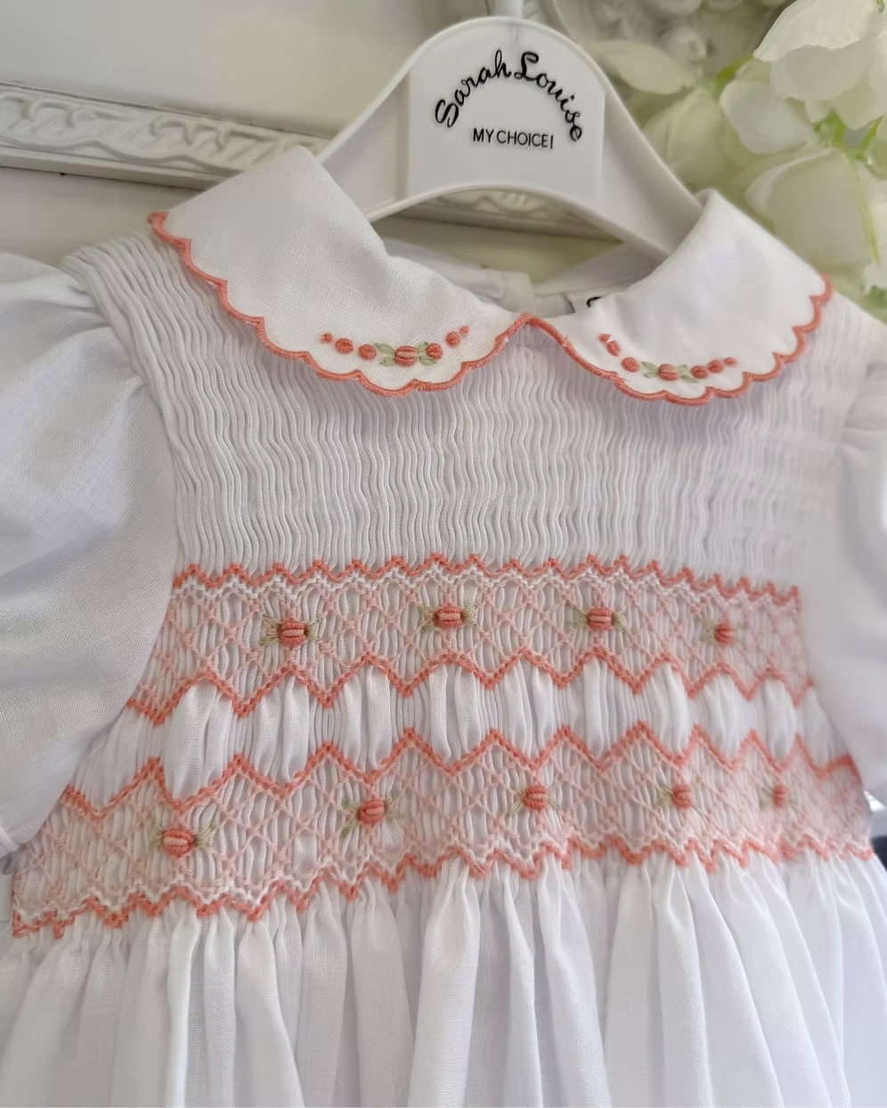 White smocked dress with peach smocking, embroidered florals and scalloped hems