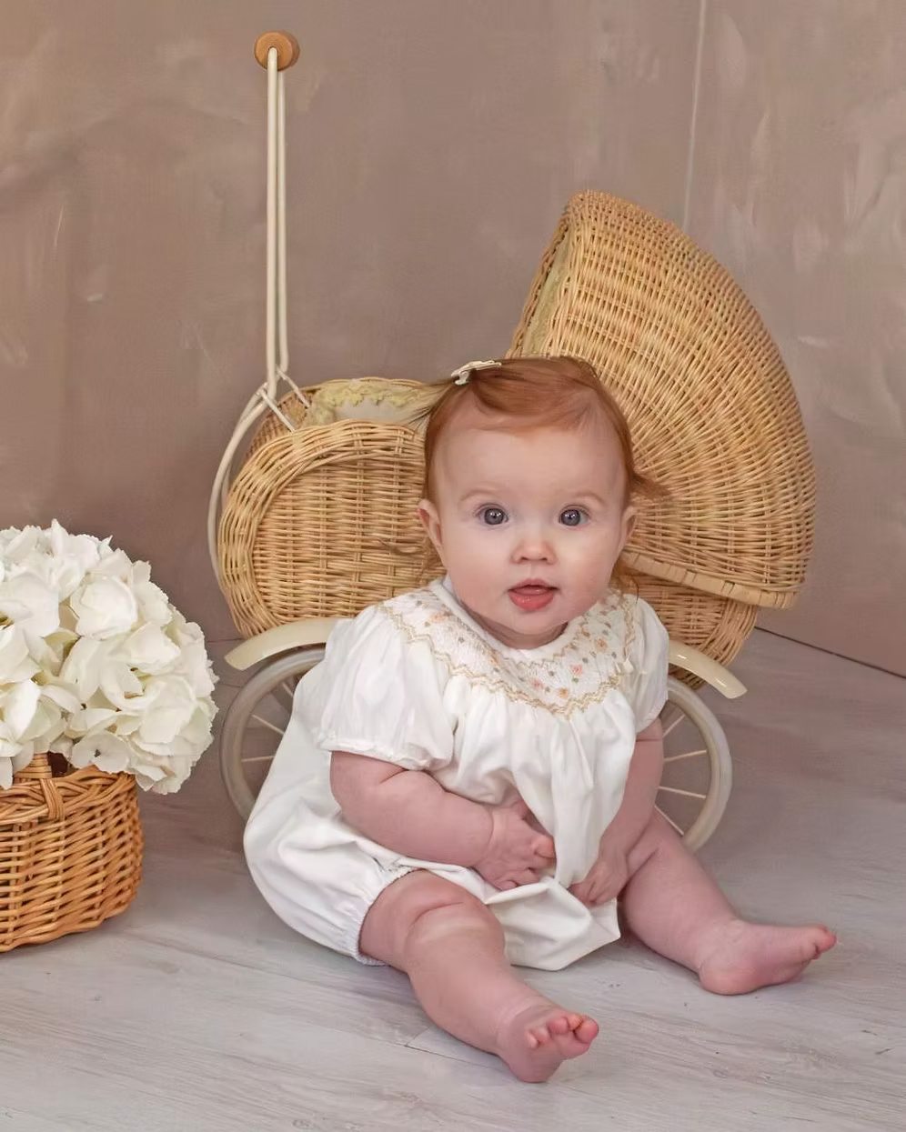 Sarah Louise x Little Lambs Heritage Bubble Romper featuring ivory fabric, hand-smocked floral embroidery, puff sleeves and a classic bubble shape.