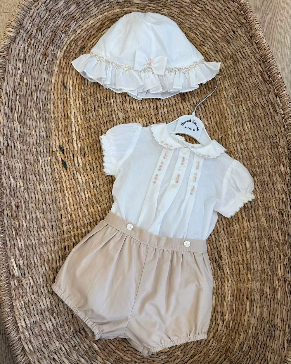Sarah Louise x Little Lambs Heritage Girls Short Set featuring an ivory hand-smocked blouse with peach embroidery and neutral tailored shorts.