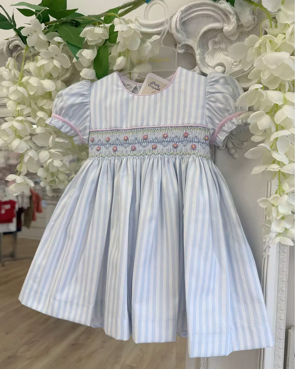 Pretty Originals Olivia Stripe Dress featuring blue and white stripes, hand-smocked rainbow embroidery, puff sleeves, matching bloomers and headband.