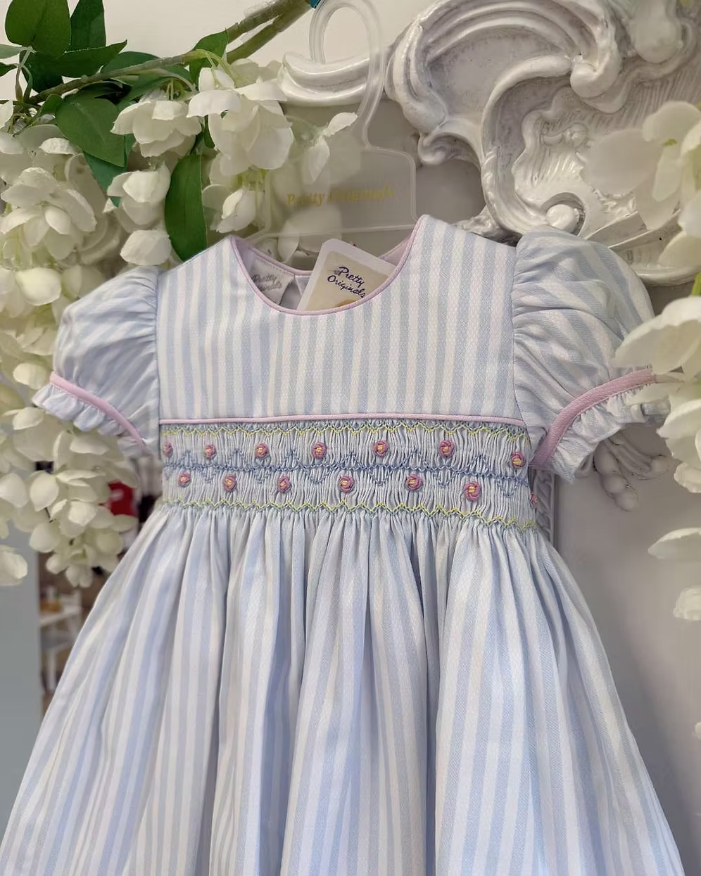 Pretty Originals Olivia Stripe Dress featuring blue and white stripes, hand-smocked rainbow embroidery, puff sleeves, matching bloomers and headband.
