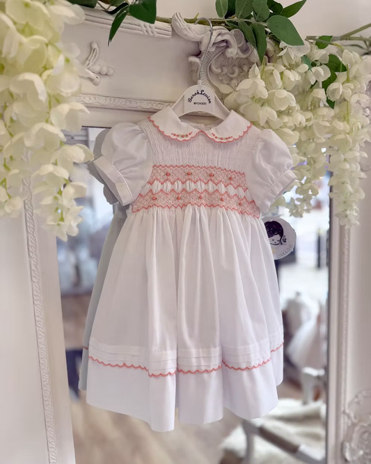White smocked dress with peach smocking, embroidered florals and scalloped hems