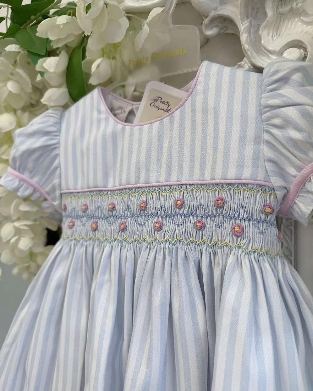 Pretty Originals Olivia Stripe Dress featuring blue and white stripes, hand-smocked rainbow embroidery, puff sleeves, matching bloomers and headband.